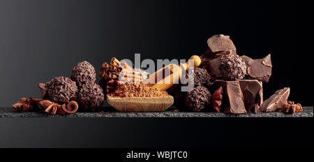 Tartufi di cioccolato con pezzi rotti di cioccolato e di spezie. Cioccolato, bastoncini di cannella e anice su uno sfondo scuro. Copia dello spazio. Foto Stock