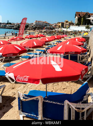 Coca Cola branded ombrelloni e sdraio sulla spiaggia di Cascais, Portogallo. Foto Stock