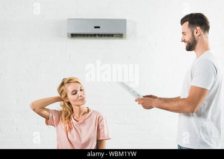 Giovane che soffre di calore sotto il condizionatore d'aria di casa Foto Stock