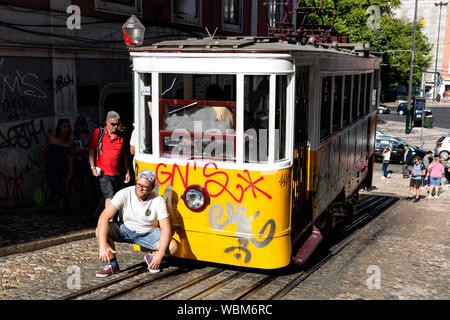 Tourist in posa davanti un graffiti coperte funicolare tram, Lisbona, Portogallo. Foto Stock