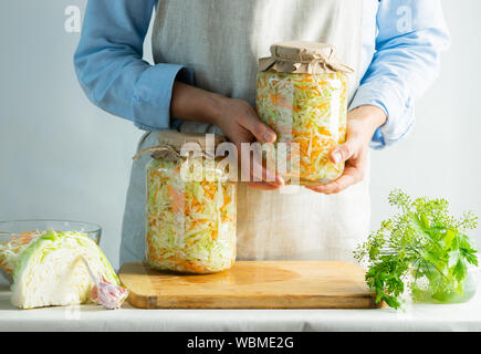 Conservazione di fermentazione crauti in vasetti di vetro nelle mani di una donna sfondo naturale. Elaborazione del raccolto autunnale. Copia dello spazio. Conserve di ve Foto Stock