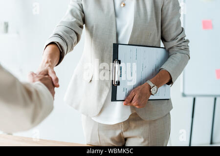 Vista ritagliata del reclutatore e il dipendente si stringono la mano in ufficio Foto Stock
