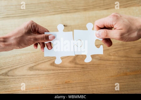 Vista ritagliata della african american donna e uomo azienda puzzle di pezzi Foto Stock