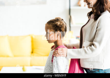 Vista ritagliata della madre di toccare le spalle della figlia nello zaino Foto Stock