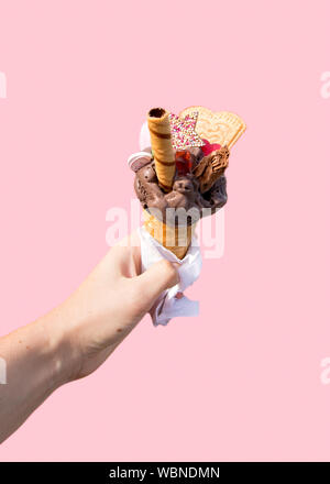 Splendidamente decorate cioccolato gelato in cono di wafer. Candy amore cuore, stella con un pizzico, wafer al cioccolato rotolo, gummi orso e pezzetti di cioccolato Foto Stock