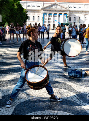 Due femmina buskers suonando la batteria in piazza Rossio per i turisti, Lisbona, Portogallo. Foto Stock