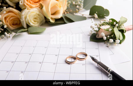 Pianificazione di nozze con anelli d oro su data nel calendario Foto Stock