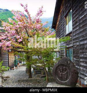 Un grazioso angolo di Narai sul sentiero Nakasendo nella Kiso Valley, Giappone, con albero ciliegio e monumento di pietra Foto Stock