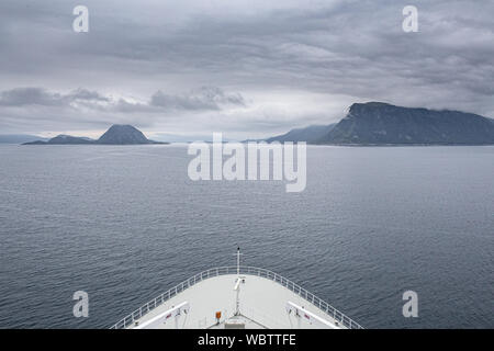 Prua di una nave da crociera rivolta verso montagne distanti come delicatamente le vele nella città di Bergen nei fiordi norvegesi Foto Stock