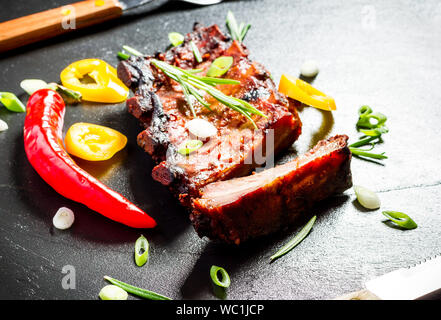 Spareribs grigliate sulla piastra di ardesia con posate, vista dall'alto Foto Stock