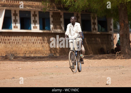 TORIT, SUD SUDAN-febbraio 20, 2013: studente non identificato cavalca la sua bicicletta dalla scuola nel villaggio di Torit, sud Sudan Foto Stock