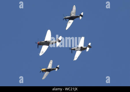 Il "Storico fighters' team di quattro guerra mondiale due combattenti, P-51, P-47, Spitfire e Buchon nella formazione di overhead aviosuperficie Wattisham. Foto Stock
