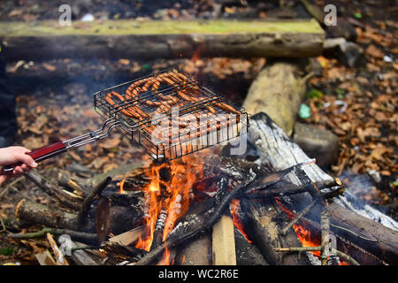 In autunno il barbecue nella natura - salsicce fritte sul fuoco. Foto Stock