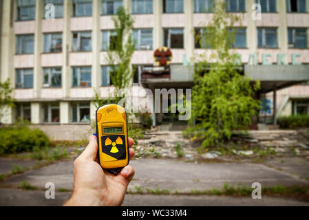 Un dosimetro in mani con un livello di radioattività nella città di pripjat, una città fantasma della centrale nucleare di Cernobyl colpiti da una centrale nucleare dis Foto Stock