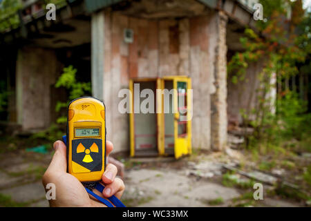 Un dosimetro in mani con un livello di radioattività nella città di pripjat, una città fantasma della centrale nucleare di Cernobyl colpiti da una centrale nucleare dis Foto Stock