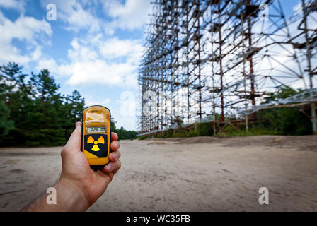 Il dosimetro in mani con un livello di radioattività a 0,27 radiazione gamma, l'ex militare di sistema radar Duga in Chernobyl Zona di esclusione, Ukrai Foto Stock