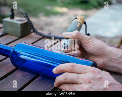 L'uomo l'incisione di un numero in una bottiglia di colore blu per utilizzarla come numero del posto di osservazione in un orto. Foto Stock