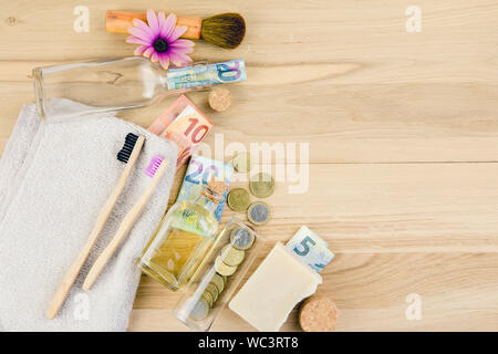 Insieme di diversi rifiuti zero prodotti di bellezza su sfondo di legno con denaro euro banconote attorno a loro, rifiuti zero uno stile di vita sostenibile vero costo di co Foto Stock
