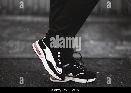 Primo piano verticale selettivo di una persona che indossa nero e. sneaker bianche Foto Stock