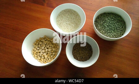 Materie semi di riso, la canapa, piselli e flaxseeds in bianco ciotole sul tavolo di legno Foto Stock