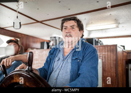 Capitano al timone di una nave da pesca Foto Stock
