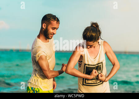 Fitness felice la gente sulla spiaggia al tramonto la flessione che mostra i muscoli Foto Stock