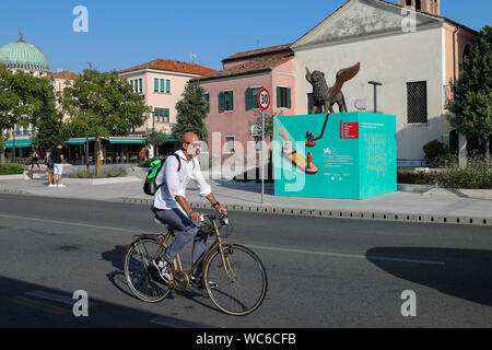 Venezia, Italia. Il 27 agosto, 2019. Un uomo passa su un cartellone per la 76th Venice International Film Festival di Venezia Lido, Italia, il 27 agosto, 2019. La 76th Venice International Film Festival si kick off qui il mercoledì. Credito: Zhang Cheng/Xinhua/Alamy Live News Foto Stock