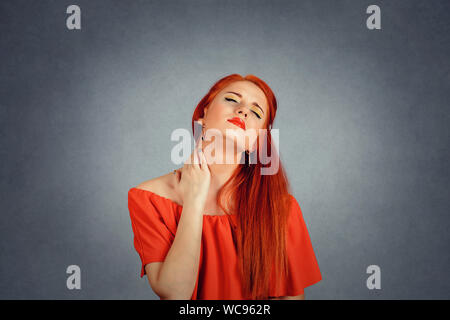 Indietro e la spina dorsale della malattia. Closeup ritratto stanco donna massaggiare la sua dolorosa collo isolato su sfondo rosso. Volto umano espressione. Stanchezza cronica dis Foto Stock