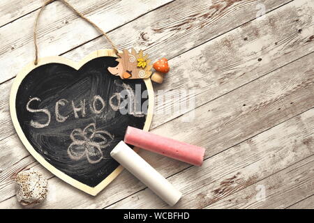 Si torna a scuola concetto. Scuola di parola scritta a mano con il gesso sulla a forma di cuore ad Blackboard. Vista superiore e spazio di copia Foto Stock