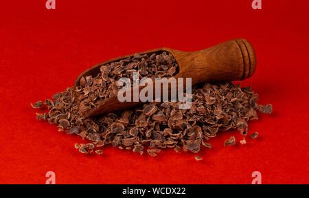 Il cioccolato grattugiato in legno isolata scoop sul rosso, colore di sfondo e primo piano Foto Stock