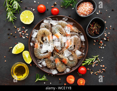 Crudo fresco gamberi e spezie su sfondo nero Foto Stock