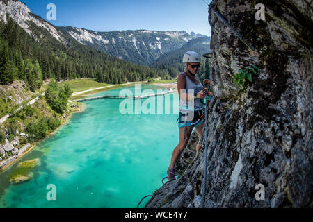 Una donna si sale la via ferrata sopra Lac de la rosière accanto al francese stazione sciistica di Courchevel nelle Alpi durante l'estate. Foto Stock