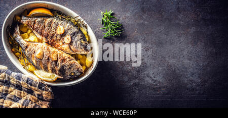 Arrosti di pesce del Mediterraneo orate con patate di rosmarino e di limone Foto Stock