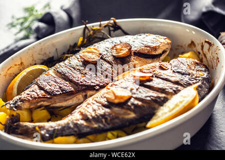 Arrosti di pesce del Mediterraneo orate con patate di rosmarino e di limone Foto Stock