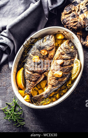 Arrosti di pesce del Mediterraneo orate con patate di rosmarino e di limone Foto Stock