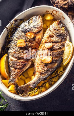 Arrosti di pesce del Mediterraneo orate con patate di rosmarino e di limone Foto Stock