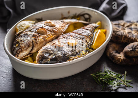 Arrosti di pesce del Mediterraneo orate con patate di rosmarino e di limone Foto Stock