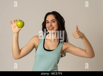 Splendida palestra latino giovane donna che mostra verde mela sensazione forte, montare e felice di frutta dopo gli esercizi di allenamento in nutrizione e fitness, H Foto Stock