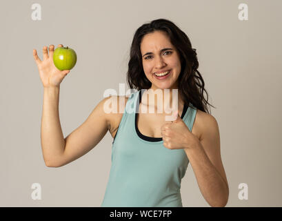 Splendida palestra latino giovane donna che mostra verde mela sensazione forte, montare e felice di frutta dopo gli esercizi di allenamento in nutrizione e fitness, H Foto Stock