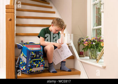 Disppointed boy, 8 anni, a casa con la sua scuola primaria relazione. Foto Stock