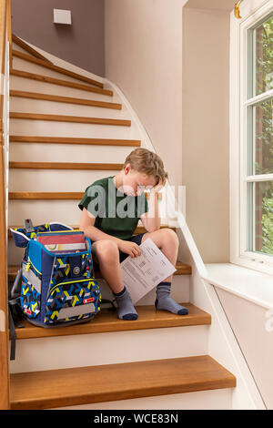 Disppointed boy, 8 anni, a casa con la sua scuola primaria relazione. Foto Stock