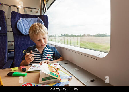 Il ragazzo, 6 anni, disegno durante il viaggio in treno, Germania, 01.08.2019. Foto Stock