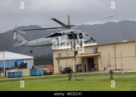 Stati Uniti Marines con 3° Battaglione di ricognizione, terza divisione Marine, condotta elicottero corda di formazione della sospensione da un MH-60S Seahawk elicottero durante l'esercizio HYDRACRAB in Santa Rita, Guam, 19 Agosto, 2019. HYDRACRAB è un esercizio multilaterali condotti dalla U.S. Marines e marinai con servizio militare membri provenienti da Australia, Canada e Nuova Zelanda. Lo scopo di questa esercitazione è quello di preparare i partecipanti l'eliminazione degli ordigni esplosivi le forze per operare come un sistema integrato, capace e efficace allied force pronto a funzionare in un mutevole e complesso ambiente marittimo in tutta l'Indo-P Foto Stock