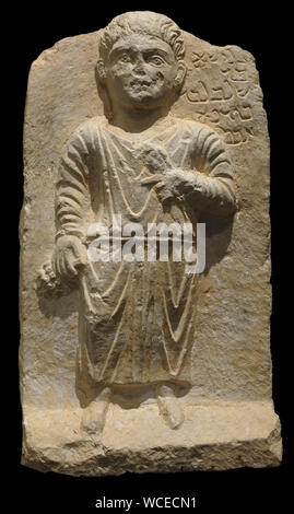 Stele funeraria calcare raffigurante la figura di una gioventù tenendo uva e un gambo di grano, con una iscrizione in lingua Palmyran dal periodo tardo romano, 200-300 CE in Palmyra Foto Stock