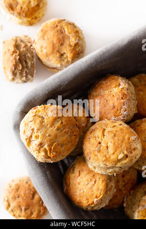 Concetto di alimenti freschi di forno in casa burrosa, salato prosciutto e formaggio scones su sfondo bianco Foto Stock