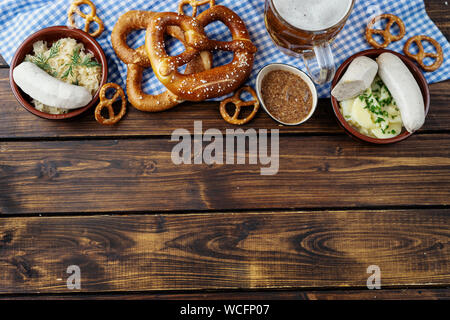 Boccale di birra, salatini e salsicce su un tavolo di legno. Vista superiore Foto Stock