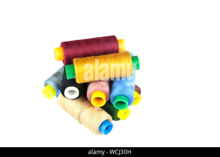 Bobine di coloratissimi fili di cucitura sovrapposti e isolati contro uno sfondo bianco. Foto Stock
