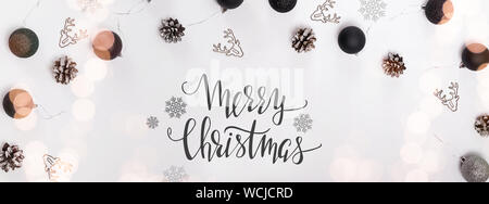 Banner con moderne decorazioni di Natale, effetto di luce e di testo. Lay piatto con sfere, cervi graffe sagomate Foto Stock