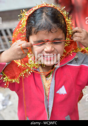 Ragazza bambino mendicante dando alle espressioni di telecamera in colorato abito religioso. Foto Stock