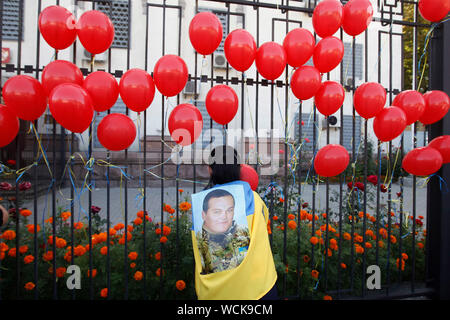 Kiev, Ucraina. 28 Agosto, 2019. Una donna imposta su un recinto dell'Ambasciata russa rosso simbolico di palloncini, durante un rally a Kiev.ucraini segnare il quinto anniversario della battaglia Ilovaysk a est dell'Ucraina, e raccolte in memoria di perso i soldati ucraini. Secondo l'Ucraina funzionari, 366 soldati ukrainiens sono andati persi e 158 erano mancanti durante i pesanti combattimenti tra il governo ucraino forze e russo-backed separatisti all'Ucraina orientale nei pressi della città Ilovaysk in agosto 2014. Credito: SOPA Immagini limitata/Alamy Live News Foto Stock